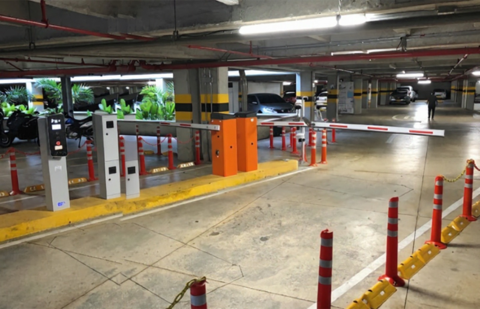 Parqueadero cubierto con barreras de control de acceso y equipos de pago